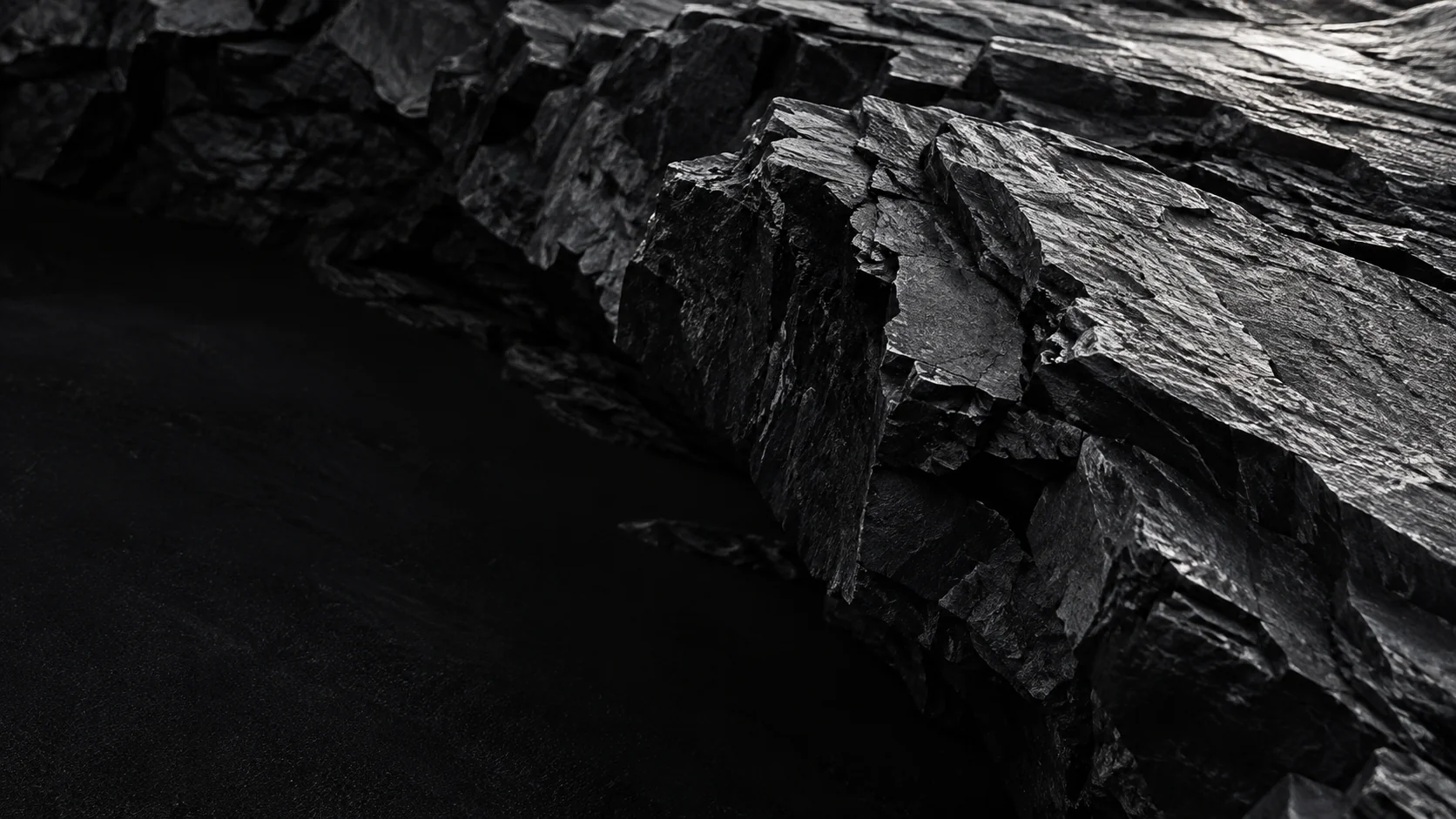 Layered dark basalt with silver light revealing its rugged surface